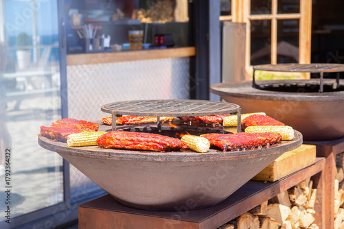 A piece of meat and ears of corn are grilled. Barbecue outside in a local cafe on an open fire
