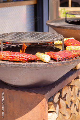 A piece of meat and ears of corn are grilled. Barbecue outside in a local cafe on an open fire