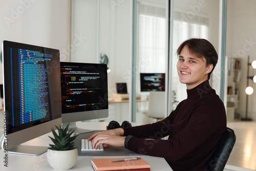 Εκτύπωση καμβά Portrait of smiling programmer working on computer with dual monitors at white t