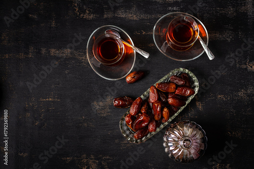 Ramadan food and drink concept. Tasty Eastern sweets and tea on dark background.