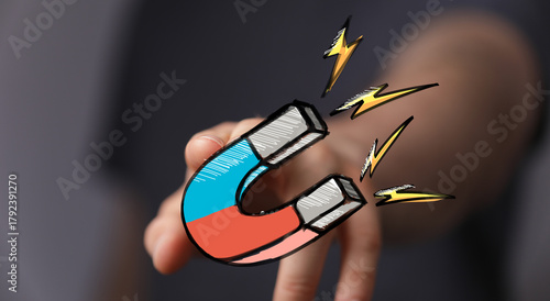 Hand holding a magnet, symb...