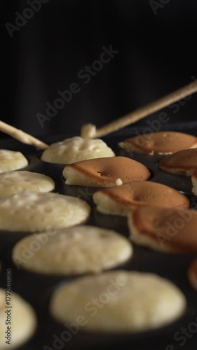 Hand of chef flip small round pancakes on hot surface delicious snack