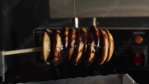 Man chef put chocolate syrup on delicious mini pancakes in the box