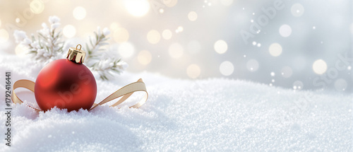 Red Christmas ornament resting in snow with shimmering background