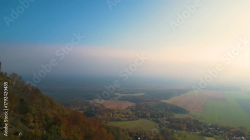 Witness the breathtaking autumn sunrise illuminating Bezdez Medieval Castle. The vibrant colors contrast beautifully with the serene landscape of Czechia, creating a captivating sight.