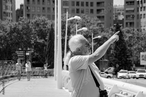 Senior man pointing finger the direction in Valencia city of Spain in the street. Retired senior man travel in Spain. Travel destination. Retirement and travel