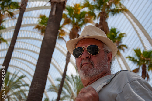 Man tourist at Valencia garden landmark. Touristic sightseeing. Travel senior man in Valencia, banner. Palm tree park Valencia. City of arts sciences in Valencia, Spain. Travel destination