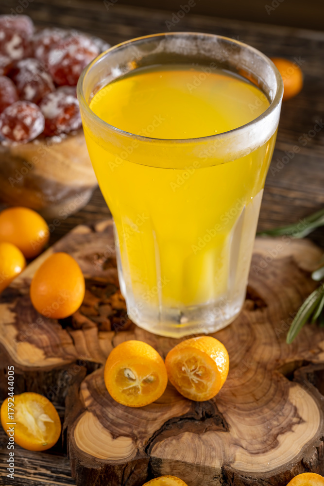 Fototapeta premium citrus-flavored orange juice and fruits on a wooden table, delicious and fresh orange juice and fresh kumquat fruits next to a glass