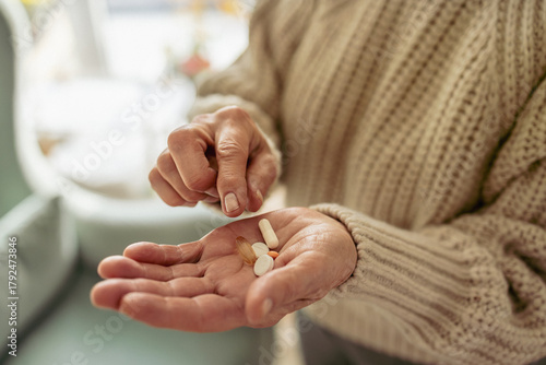 Senior woman taking her medication at home, close-up of hands
