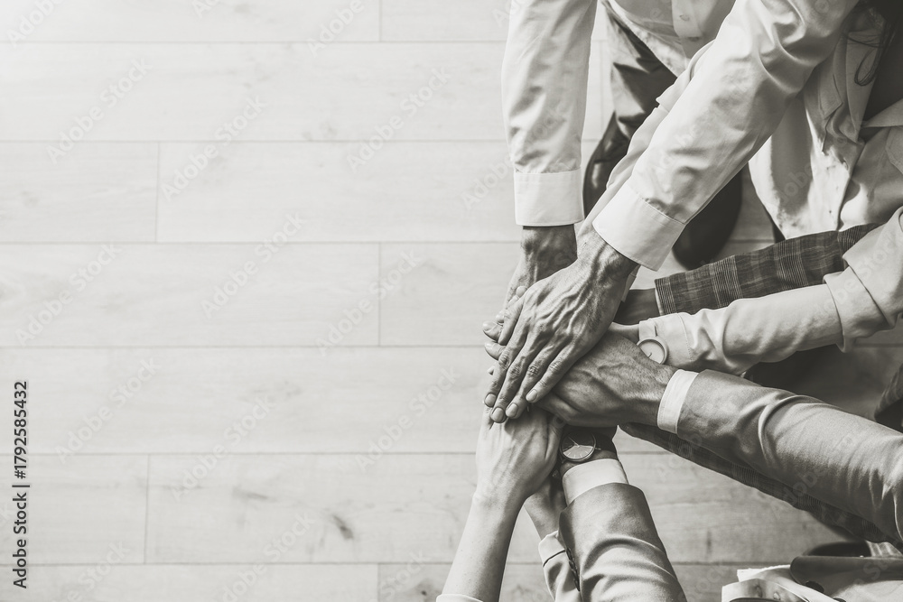 Naklejka premium People holding hands together, top view with space for text. Black and white toning. Unity concept