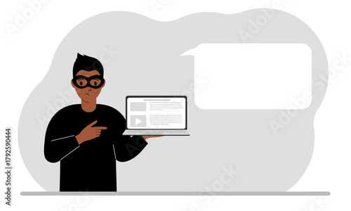 Hacker in a black mask with a computer. The cybercriminal is holding a laptop. Cyber attack, mobile phishing, scam.