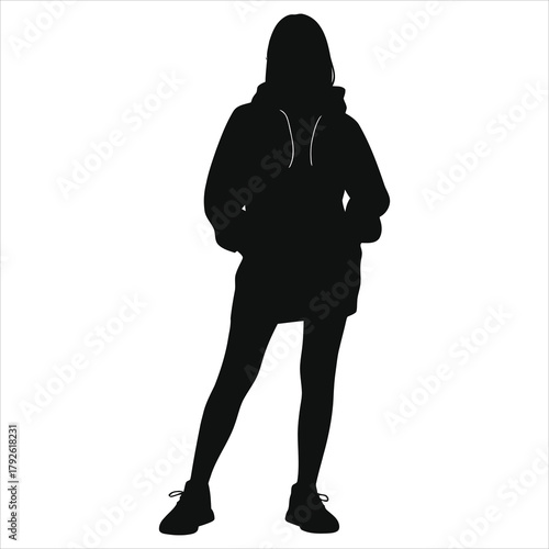 Black vector silhouette of young fashionable woman standing in sporty winter urban street fashion outfit: oversized hoodie dress, leggings, and athletic shoes. Isolated design element.