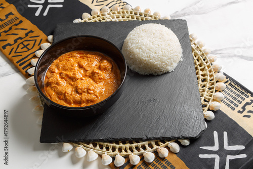 Mafé à la viande servie avec riz blanc, présenté sur une ardoise et un set de table tissé africain – plat traditionnel africain. Cuisine sénégalaise. 
