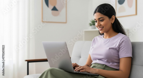 Happy young woman using laptop on sofa in living room