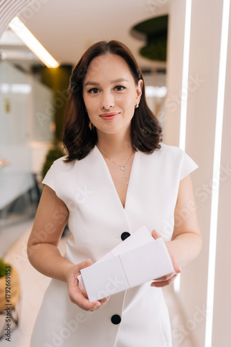 Professional female cosmetologist presenting blank cosmetic product boxes, symbolizing expertise and advertising in the beauty and healthcare industry. Concept of rejuvenating skin, preventing aging.