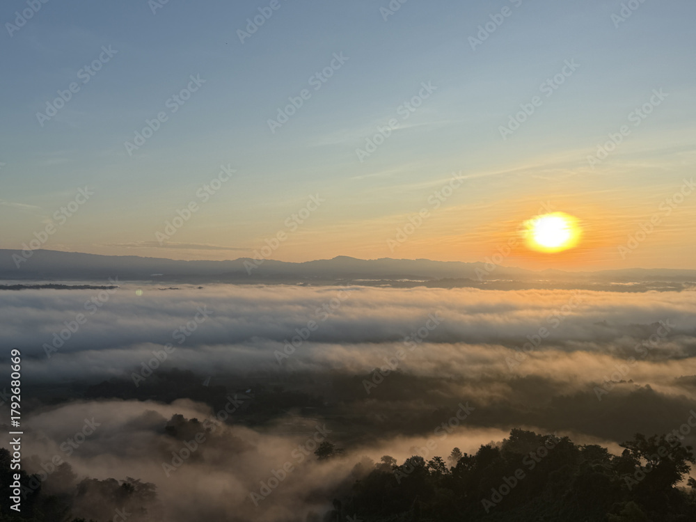 Obraz premium Sunrise over a misty valley with the sun glowing brightly