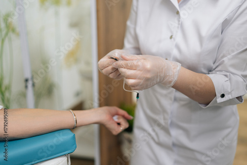 Cropped shot of unrecognizable woman patient receiving blood test preparation from medical professional, getting blood sample drawn for laboratory analysis in clinical healthcare environment.