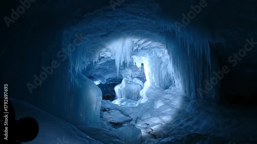 A view inside an icy cave with icicles and blue light