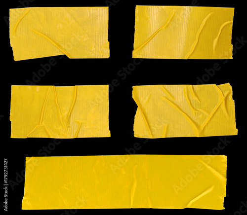 A collection of wrinkled yellow adhesive tape pieces isolated on a black background, showing creases, texture, and sticky details, perfect for graphic design, collage artwork, crafting projects,