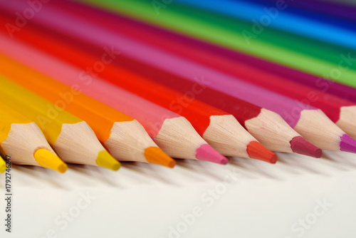 New wooden colored pencils of rainbow colors, perfectly sharpened, lie on table
