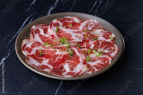 Plate of Marbled Raw Meat Slices Garnished with Fresh Herbs