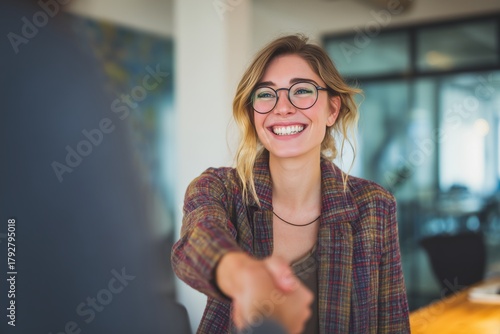 Smiling Woman Shakes Hands in a Bright Office During a Business Meeting.