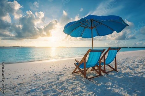 Beach Chairs Under a Blue Umbrella With a Sunset View Over the Calm Sea