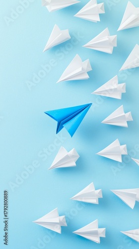 Blue Paper Airplane Leads a Group of White Paper Planes on a Bright Blue Back...