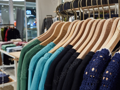 Knitted sweaters on hangers in shop for sale.