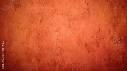 Textured reddish-orange wall with a distressed, grunge effect and dark vignette. Ideal for backgrounds, overlays, or abstract designs, blurred red background