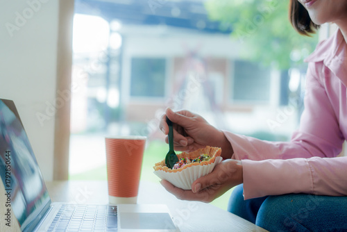 Businesswoman smiling while using laptop and talking on mobile phone at desk in office and at home or coffee shop.