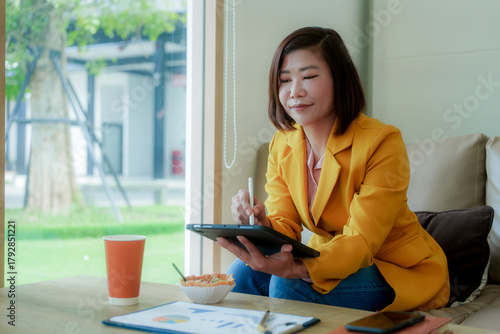 Businesswoman smiling while using laptop and talking on mobile phone at desk in office and at home or coffee shop.