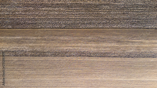 Aerial view of textured brown land with horizontal lines, representing agricultural fields or natural landscapes. The image captures the essence of natures patterns and colors.