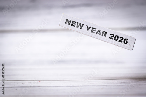 Handwritten text reading NEW YEAR 2026 on a white wooden table evokes feelings of celebration and new beginnings, perfect for planners and event organizers.