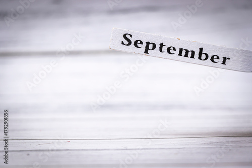 Handwritten September on a wooden sign, emphasizing the month symbolically. Represents seasonal change, autumn, and the transition into fall festivities and activities.