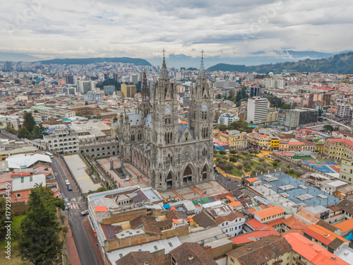 Aerial view of the magnificent Basílica del Voto Nacional pierces the sky amidst a sprawling urban tapestry, a gothic masterpiece standing tall, Quito, Ecuador.