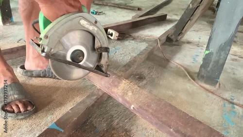 Cutting wooden log with small saw