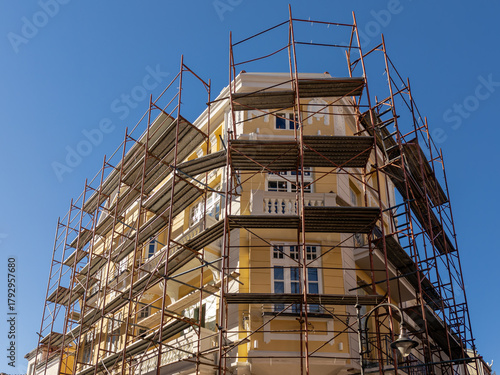 Facade restoration of a historic building with extensive metal scaffolding. Concept of urban renewal, construction, and real estate development.