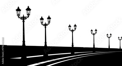 Silhouette of street lamps along a road with white lines in black and white landscape scene view