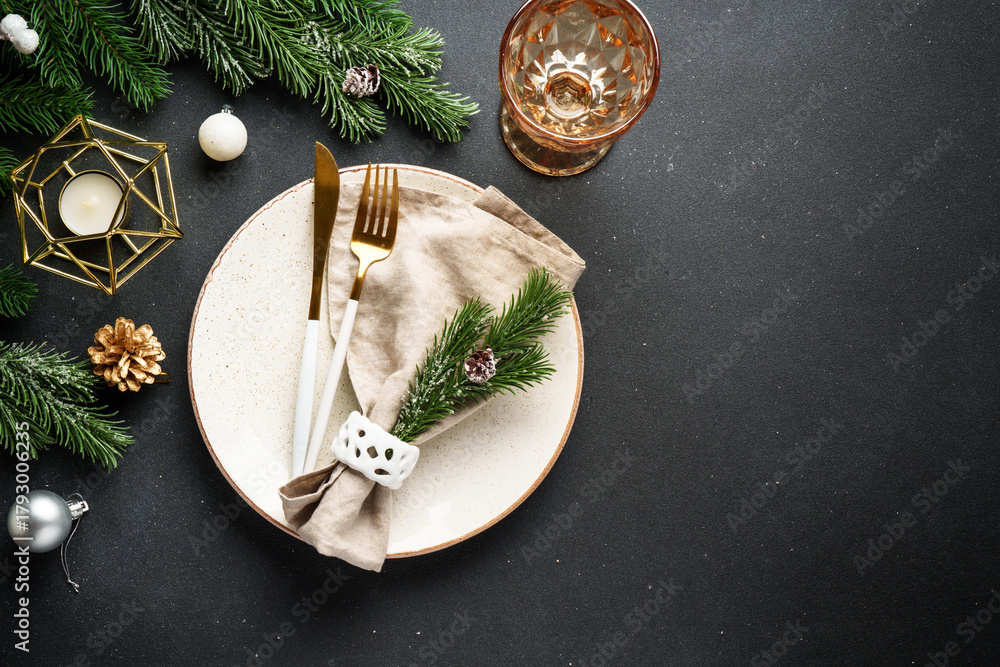 Obraz premium Christmas table setting. Christmas dinner - black plates with cutlery and decorations on black background.