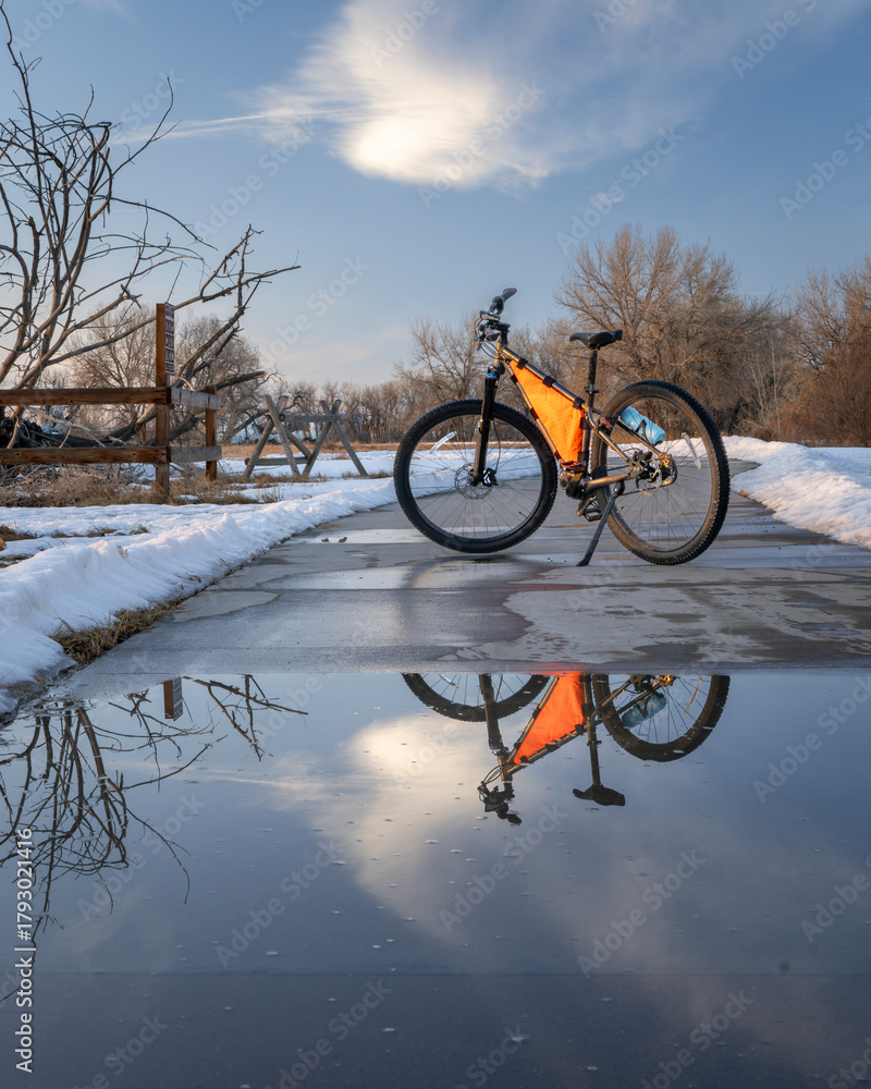 Naklejka premium mountain bike on Poudre River Trail near Greeley in Colorado, winter scenery with puddle reflection