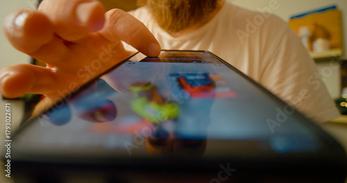 Bearded male scrolling through social media news feed on smartphone, viewing multiple screens with digital content and notifications