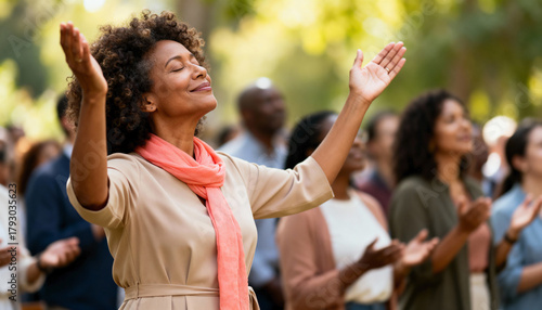 Mature Black woman with hands raised in worship during an outdoor service. Spiritual person expressing faith and praise in a diverse community