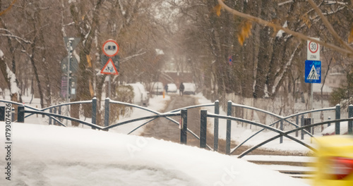 Fototapeta Naklejka Na Ścianę i Meble -  Snow blankets the urban landscape as it falls gently over streets and trees, transforming the city into a serene winter setting during the season.