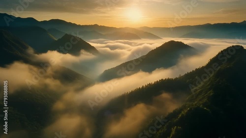 A beautiful morning sunrise casts a golden light over misty mountain peaks and forest valleys, creating a scenic landscape of clouds and fog at dawn