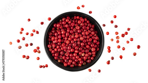 Pink peppercorn  pepperberry  in black bowl flying isolated on white background. Aromatic spicy ingredient for cuisine
