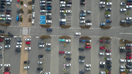 Aerial view of busy parking lot near shopping center, showcasing various parked vehicles, camera pans across scene highlighting parking dynamics and space utilization