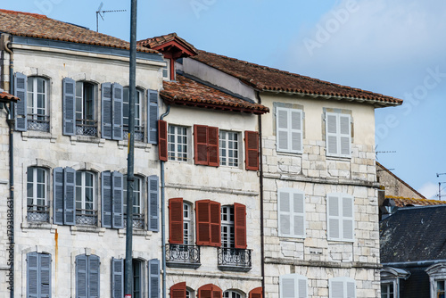 Colorful buildings with shutters in Bayonne, France, under a bright blue sky.