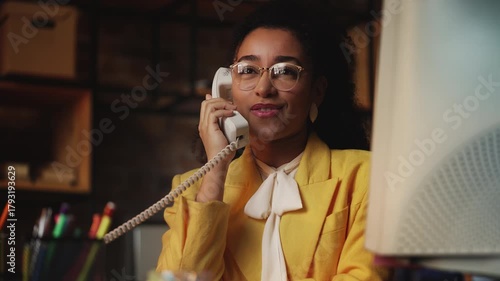Smiling African American businesswoman in vintage outfit talking on phone