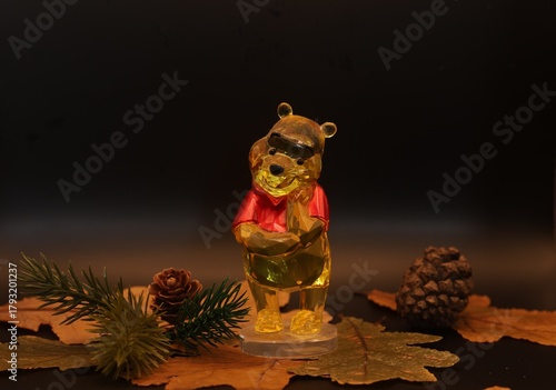 Golden Bear Figure with Pine Branch and Cone in Warm, Dark Lightning